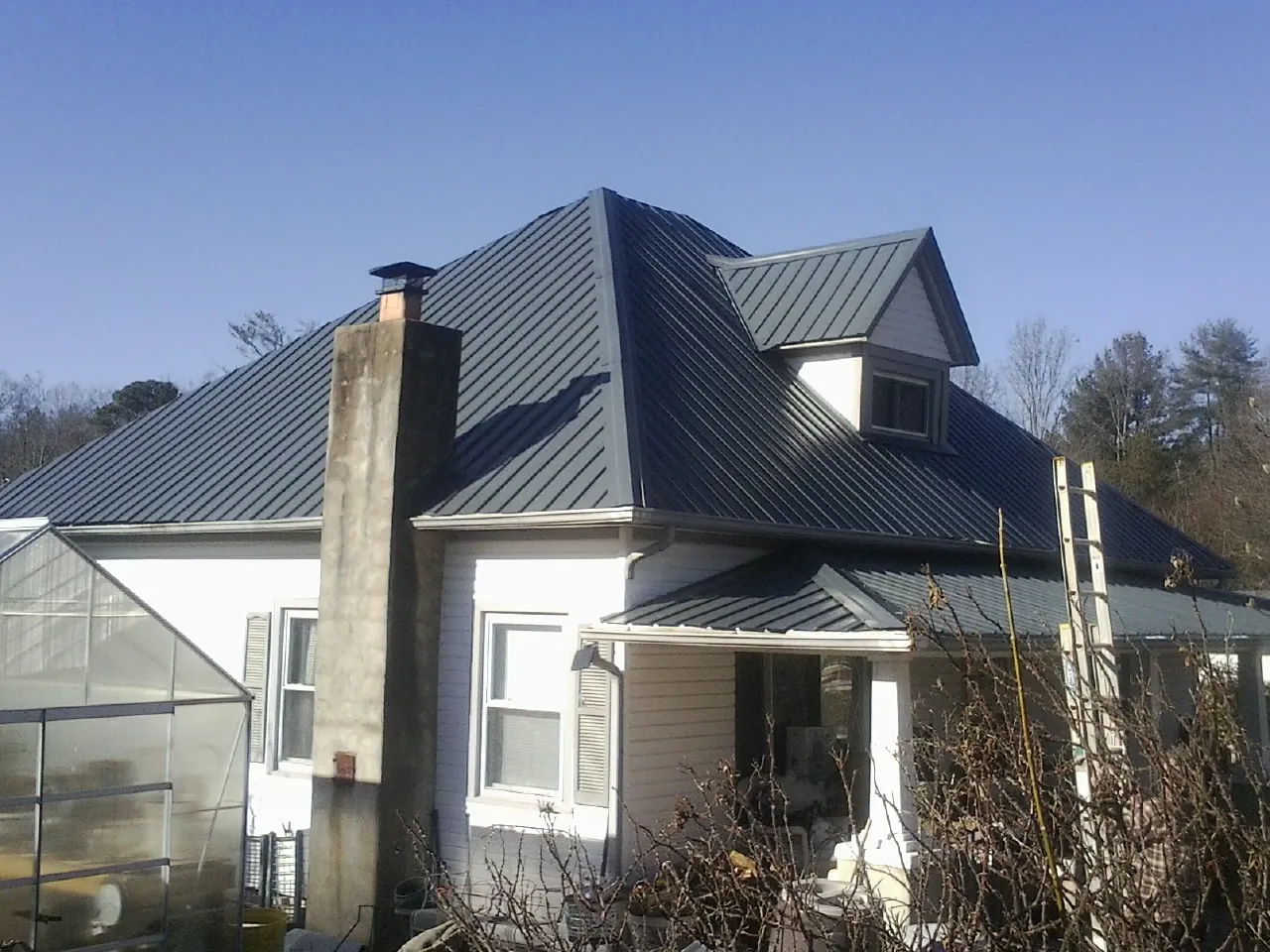 Dark blue standing seam metal roof on a white farmhouse with dormer — Slate & Tile Roof Repair by Roofing Brothers in Wenham