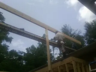 Carpenter setting a ridge beam over a new addition frame — Ice Dam Removal by Roofing Brothers in Wenham