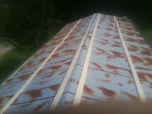 Rusted metal roof panels with new wood purlins before replacement — Storm Damage Roof Repair in Wenham by Roofing Brothers