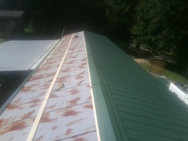 Old rusted panels beside newly installed green metal roofing — Wind Damage Roof Repair by Roofing Brothers in Wenham