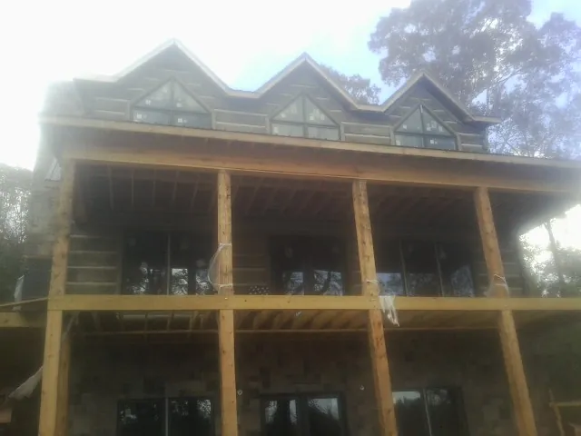 Dormers and porch framing on a large log home under construction — Roof Coating work by our crew in Wenham