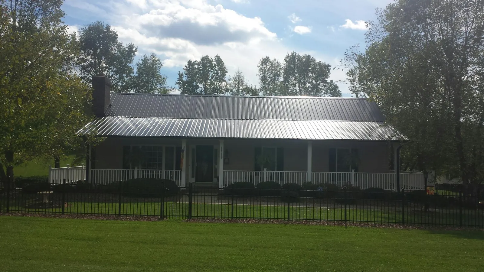 Gray metal roof on a brick ranch with a full width front porch — Gutter Guard Installation work by our crew in Wenham