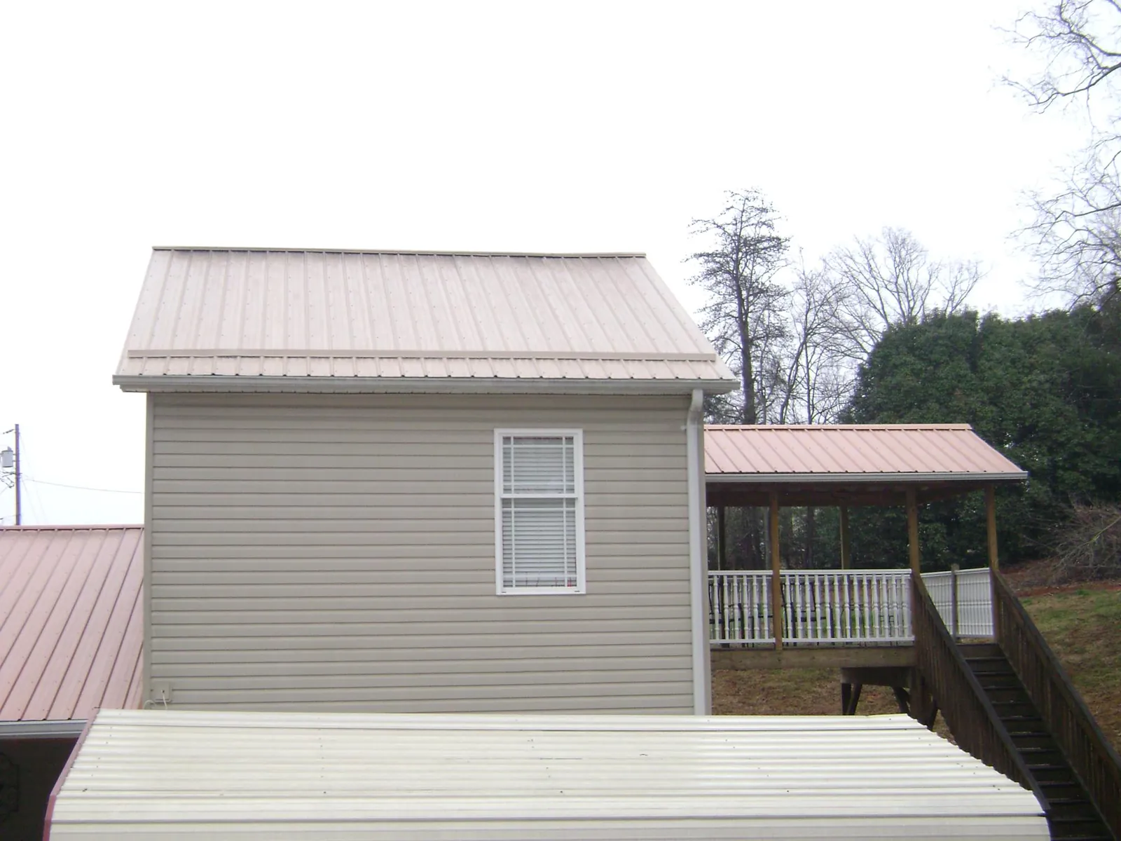 Tan metal roofs on a two story addition and attached porch, from a Roof Replacement job in Wenham